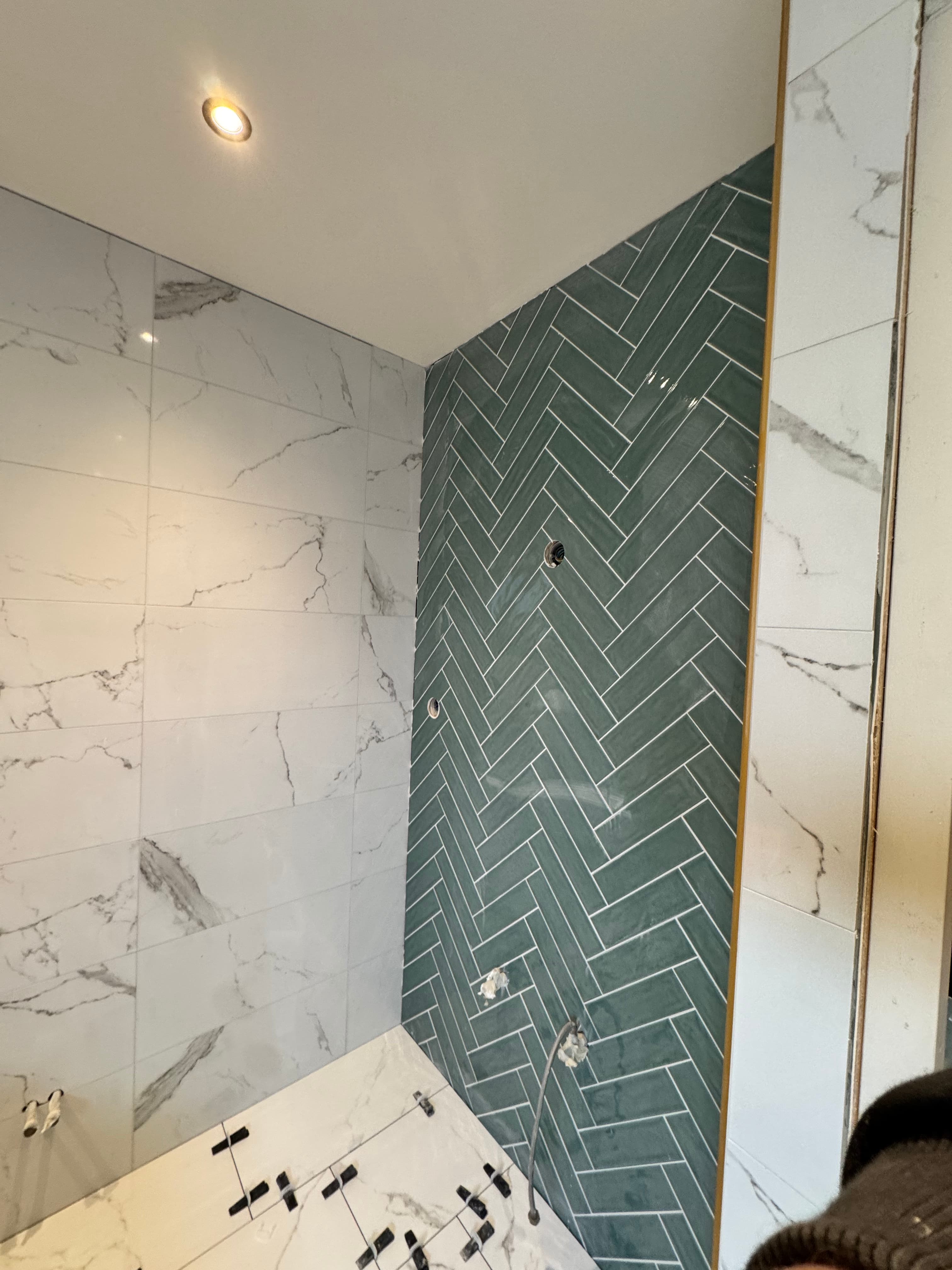 Moderne badkamer met groene visgraat wandtegels en witte marmeren tegels tijdens een renovatie.
